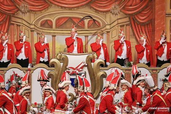 Foto des Elferrats während der großen Bürgersitzung, im Vordergrund tanzt die Tanzgruppe