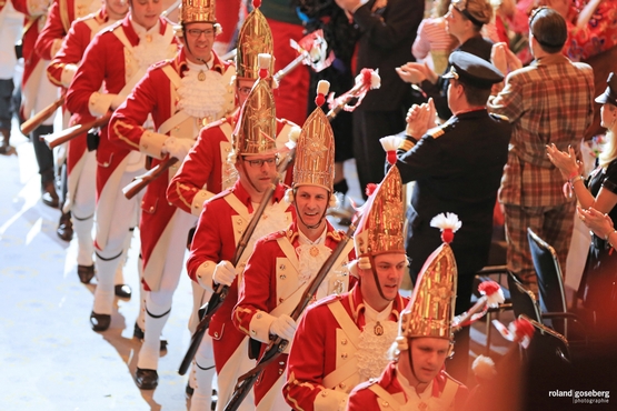 Auf diesem Foto sieht man die Ehrengardisten beim Einzug durch den Saal während Stehende Menschen klatschen