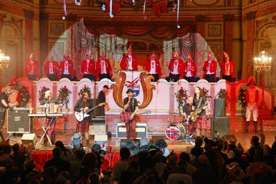 auf diesem Foto sieht man Brings auf der Bühne der großen Bürgersitzung, im hintergrud steht der Elferrat auf dem Podest