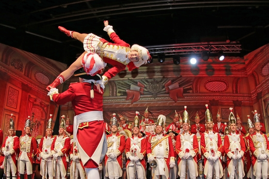 Foto von einer Hebefigur des Tanzpaares auf der Bühne, im Hintergrund stehen die Ehrengardisten und schauen gespannt zu