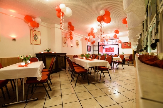 Zeughaus Interior Die Tische sind mit weißen Tischdecken geschmückt. An der Decke schweben rot-weiße Ballons.