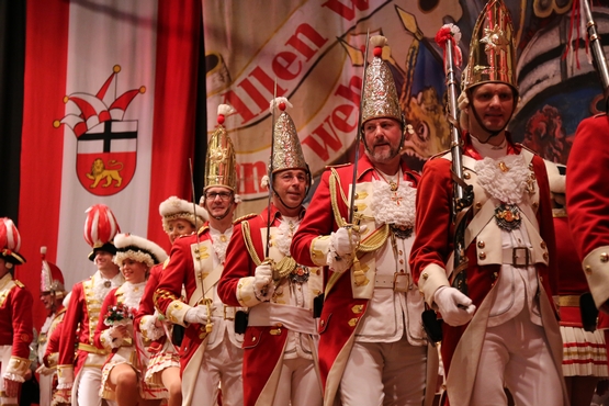 Die Ehrengardisten stehen in uniform auf der Bühne und halten ihre Säbel nach oben